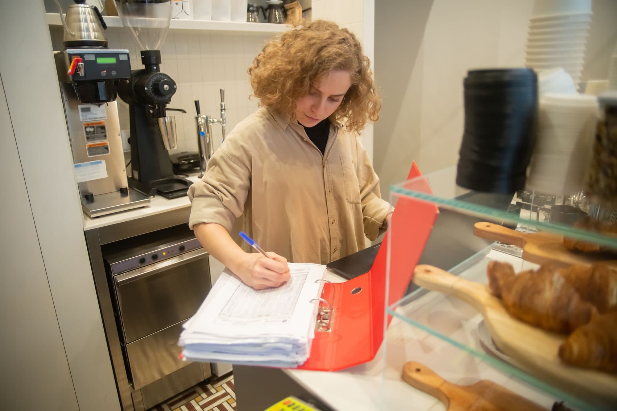 A café owner working through a folder of paperwork behind the counter