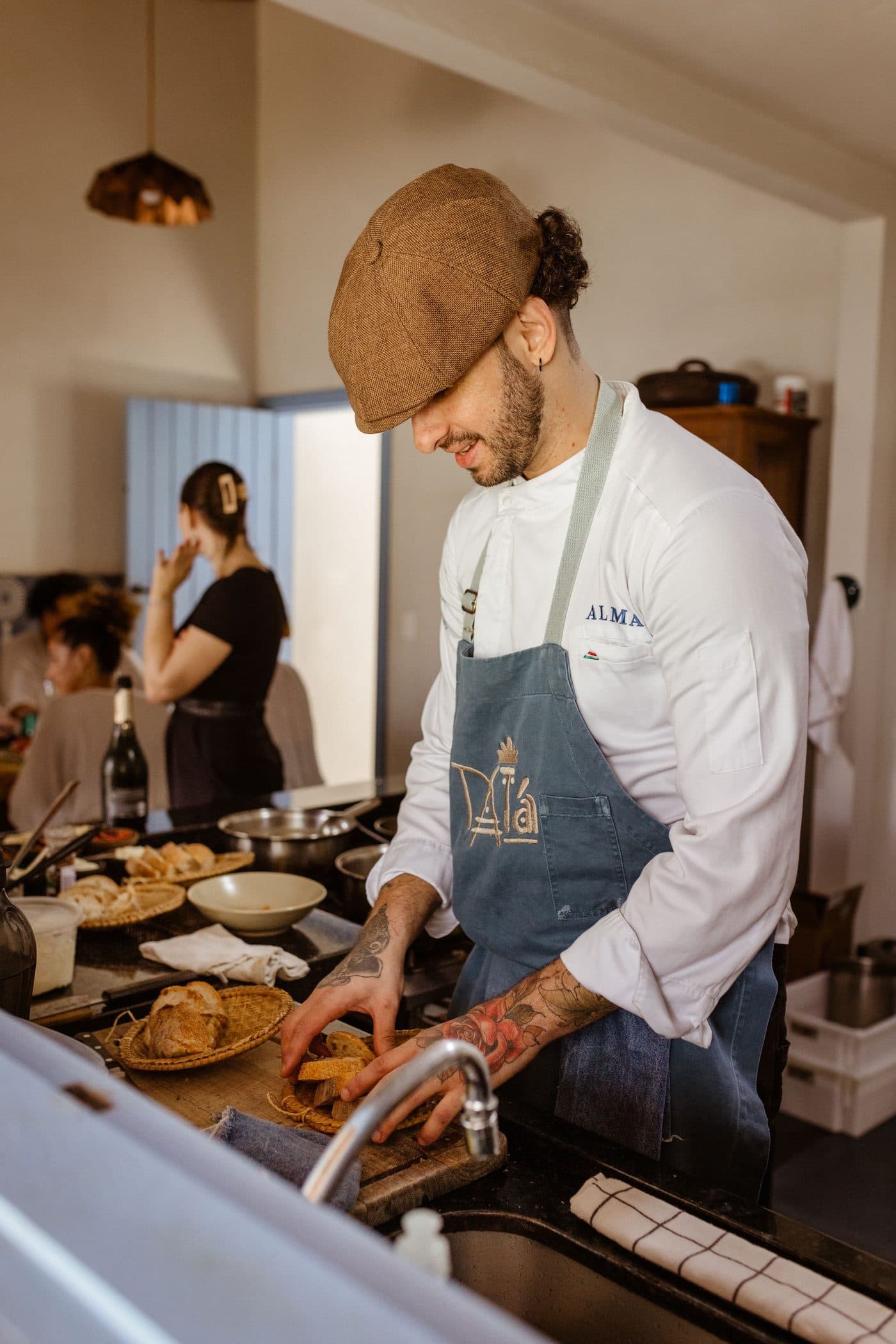 A chef in an apron and cap plating up in a busy restaurant kitchen